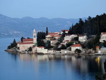 Town by lake and mountains against sky