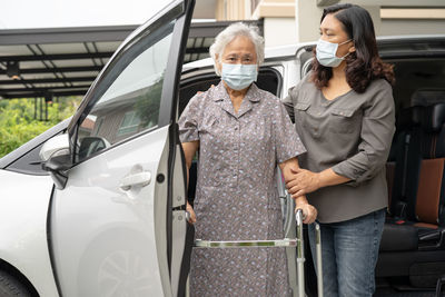 Caregiver help and support asian senior woman patient walk with walker prepare get to her car.