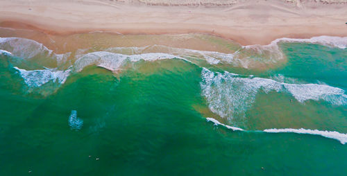 Beach from above with wafe and green ocean.