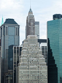 Low angle view of skyscrapers against cloudy sky