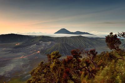 Scenic view of landscape against cloudy sky during sunset