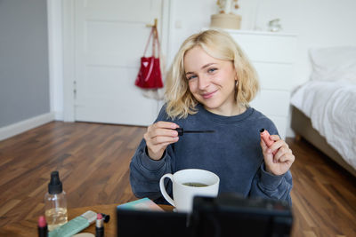 Portrait of young woman using mobile phone at home