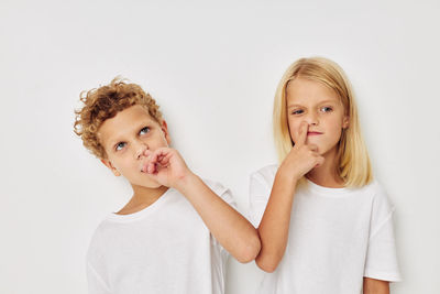 Sibling picking nose against white background