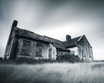 Old house on field against sky