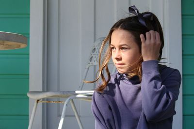 Cute girl looking away while sitting against door