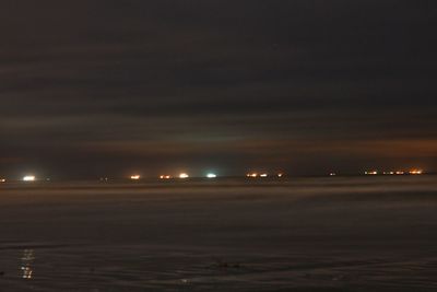 Illuminated sea against sky at night
