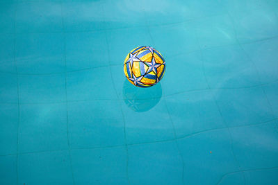 Colorful ball with print floating in water from the pool