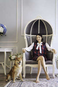 Pet lover concept. an asian woman is resting with a shiba inu dog on sofa in living room.