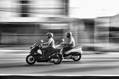 Rear view of man riding motor scooter on street