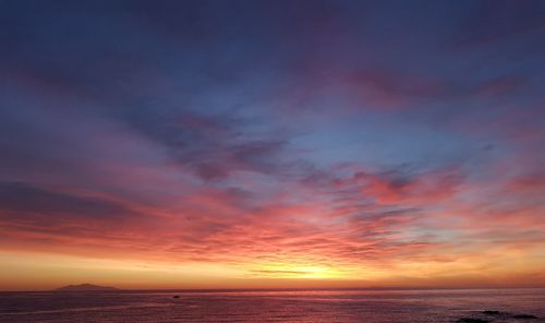 Scenic view of sea against dramatic sky during sunset