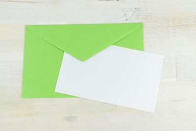 Close-up of blank paper with green envelope on table