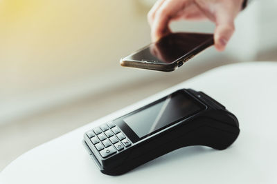 Anonymous person uses his smartphone to pay for a purchase in a store