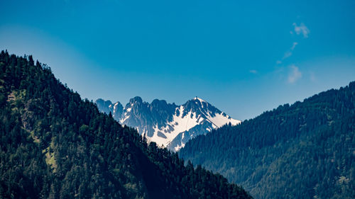 Scenic view of snowcapped mountains against blue sky