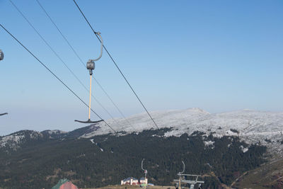 Overhead cable car on snowcapped mountains against clear sky