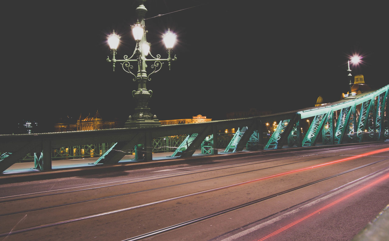 ILLUMINATED LIGHT TRAILS ON ROAD AGAINST CLEAR SKY AT NIGHT