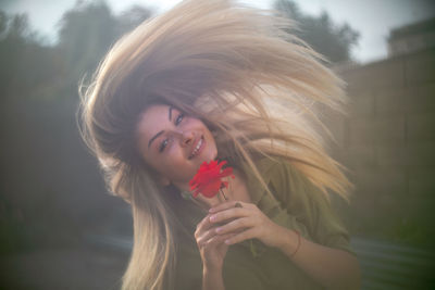 Portrait of woman holding red flowering plant