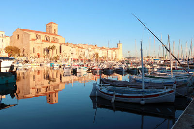 Boats moored at harbor against clear blue sky