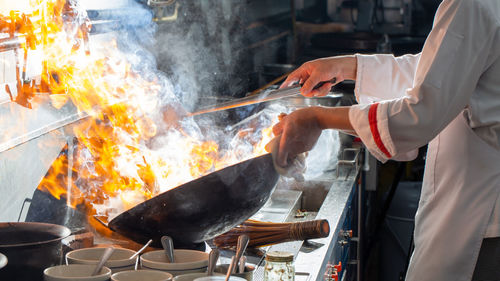 Chef stir fry cooking in kitchen, professional chef fire cooking of restaurant