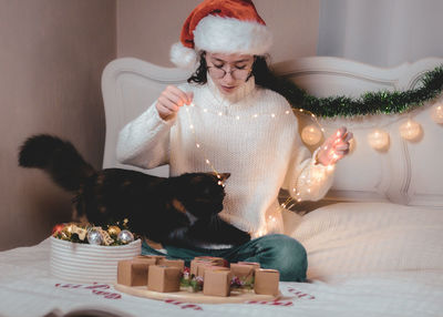 A girl plays with a cat with a burning garland.