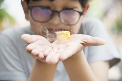 Close-up of boy holding food with smoke