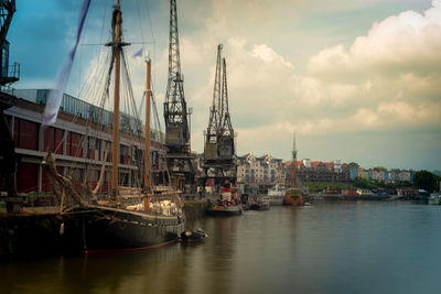 Sailboats moored at harbor against sky in city