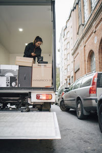 Female worker using digital tablet while analyzing packages in delivery van at city