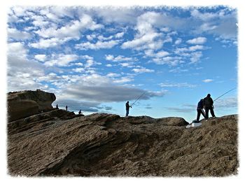 Man standing on rock against sky