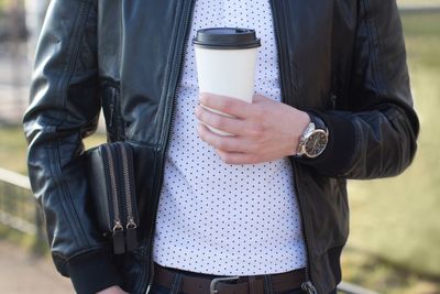 Midsection of man holding disposable cup