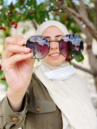 Portrait of smiling woman holding sunglasses