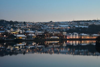 Illuminated buildings in town against clear sky