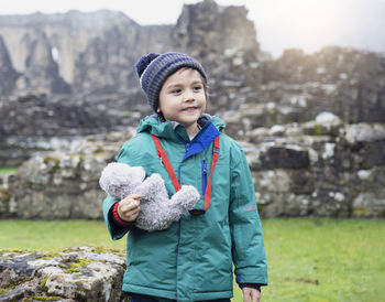 Smiling girl with toy standing on mountain during winter