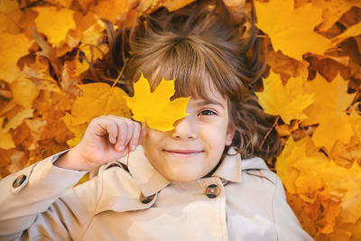 Portrait of girl lying on autumn leaves