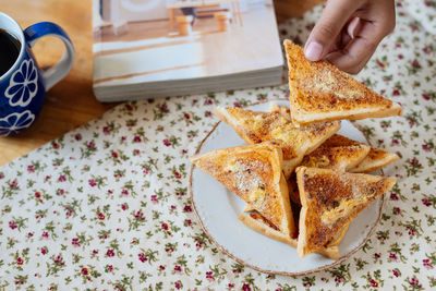 Close-up of person hand holding toasted bread on table