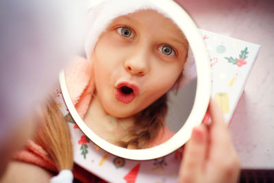 Reflection in the mirror of a christmas caucasian girl in santa's cap.