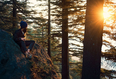 Man sitting on tree trunk in forest