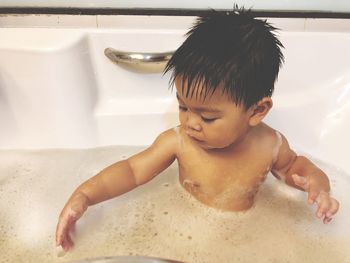 Shirtless boy taking bath in bathtub