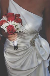 Midsection of bride holding bouquet