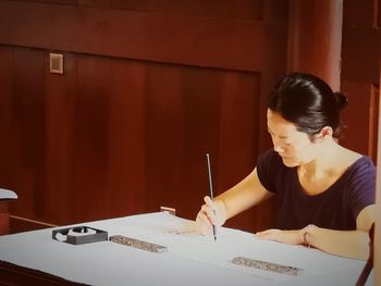 Woman working at desk against wall