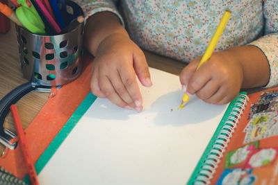 Midsection of girl writing on book