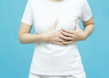 Midsection of woman holding hands against blue background