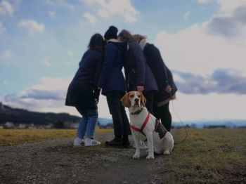 Man with dog on field against sky