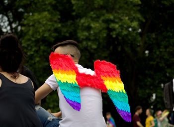 Rear view of people holding multi colored flowers