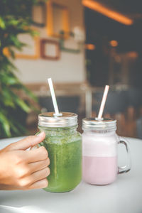 Midsection of woman holding drink on table