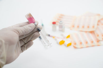 Cropped hand of doctor holding syringe over white background