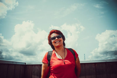 Portrait of a smiling young woman standing against sky