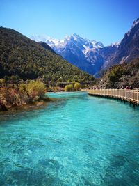 Scenic view of lake by mountains against clear blue sky