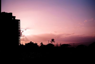 Silhouette city against sky at sunset