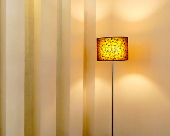 Illuminated lamp against wall at home
