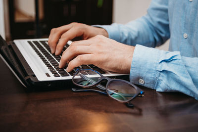 Midsection of man using laptop on table