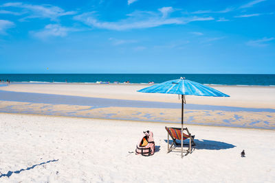 Deck chairs on beach against sky